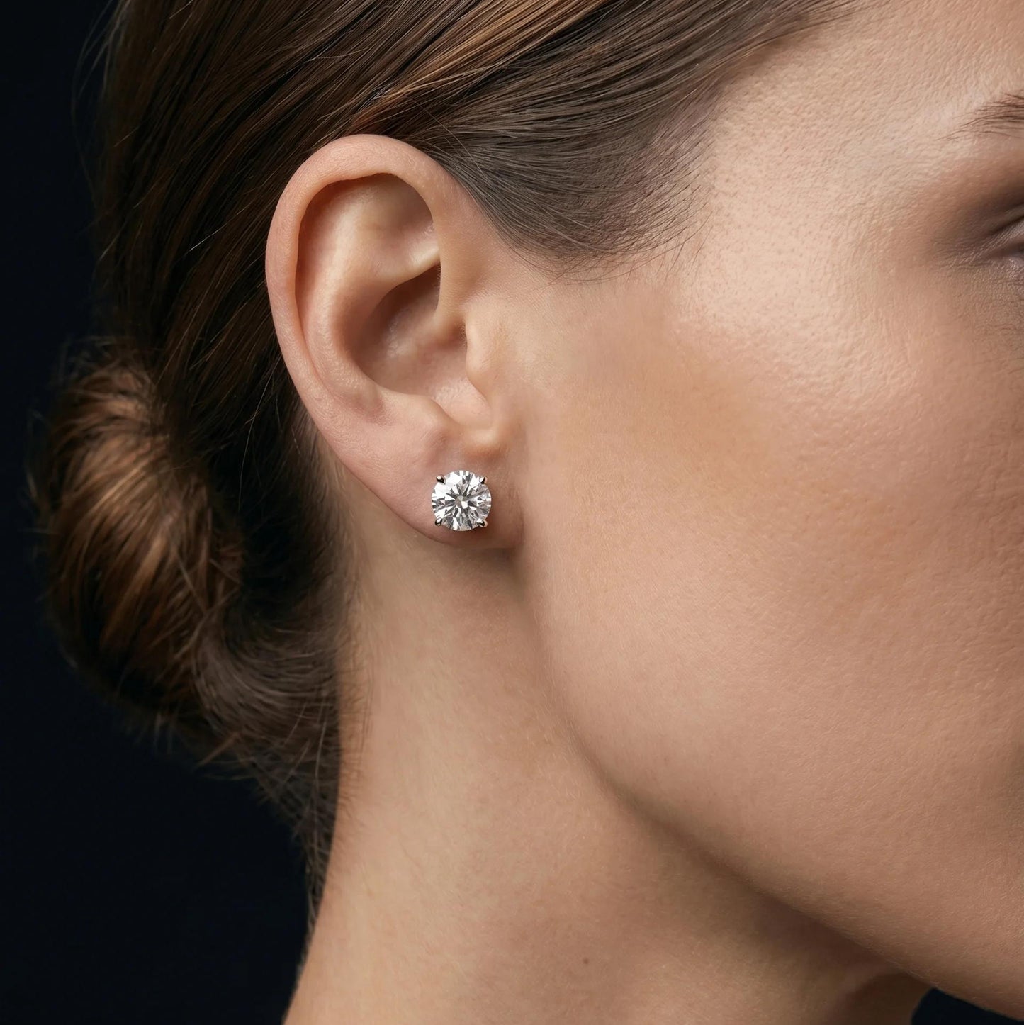 Close-up of a woman wearing a diamond earring with a dark background