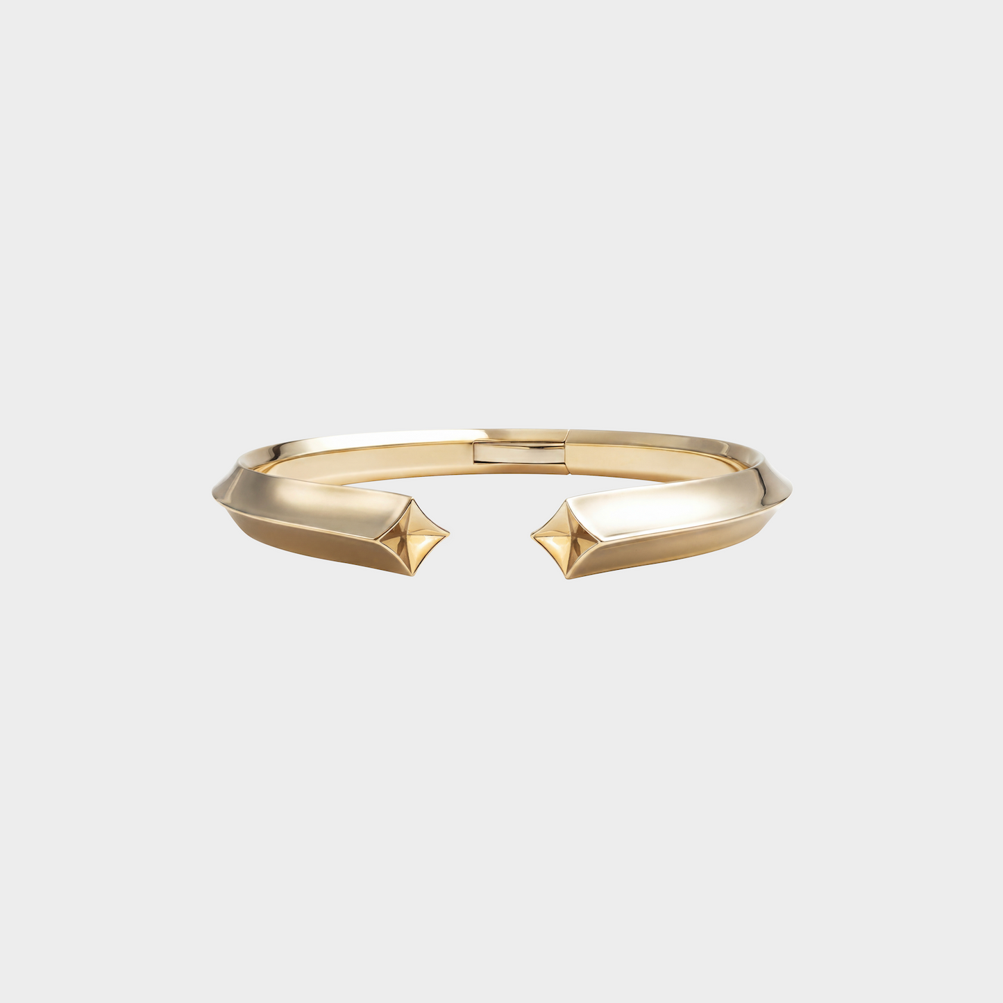 Gold bracelet with geometric design on a light gray background