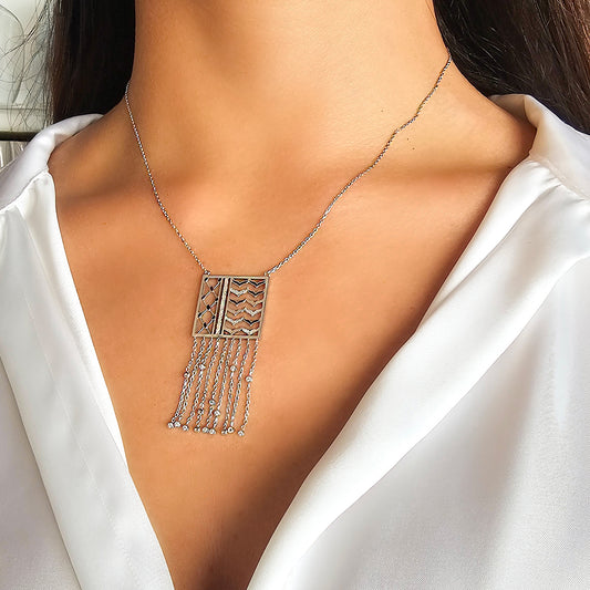Necklace with a geometric pendant worn by a person in a white outfit