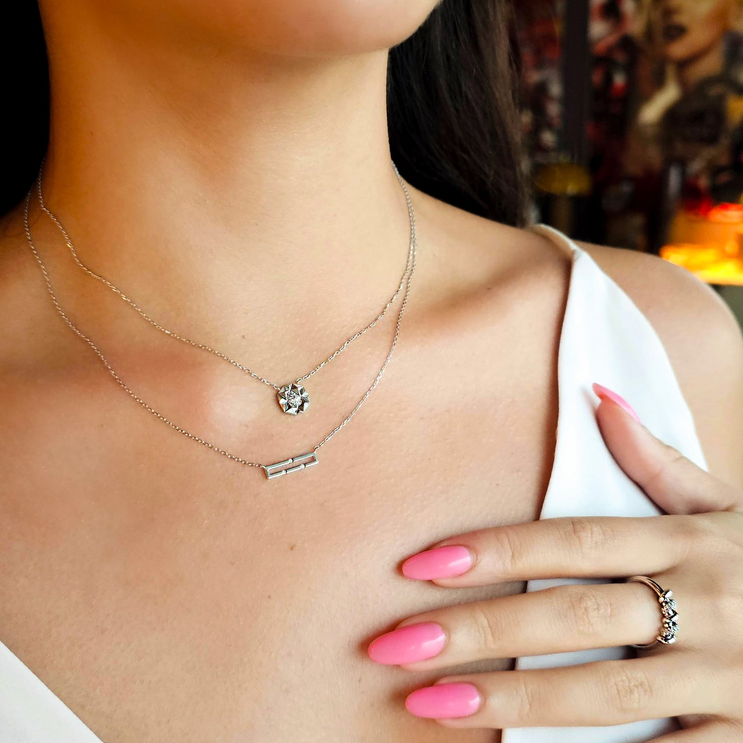 Close-up of a woman wearing a necklace and ring with a blurred background