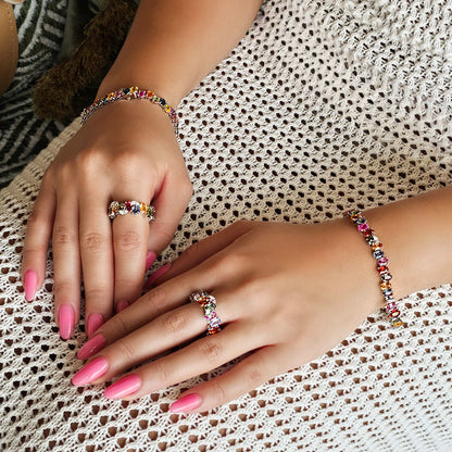 Close-up of hands wearing colorful bracelets and rings on a textured fabric background