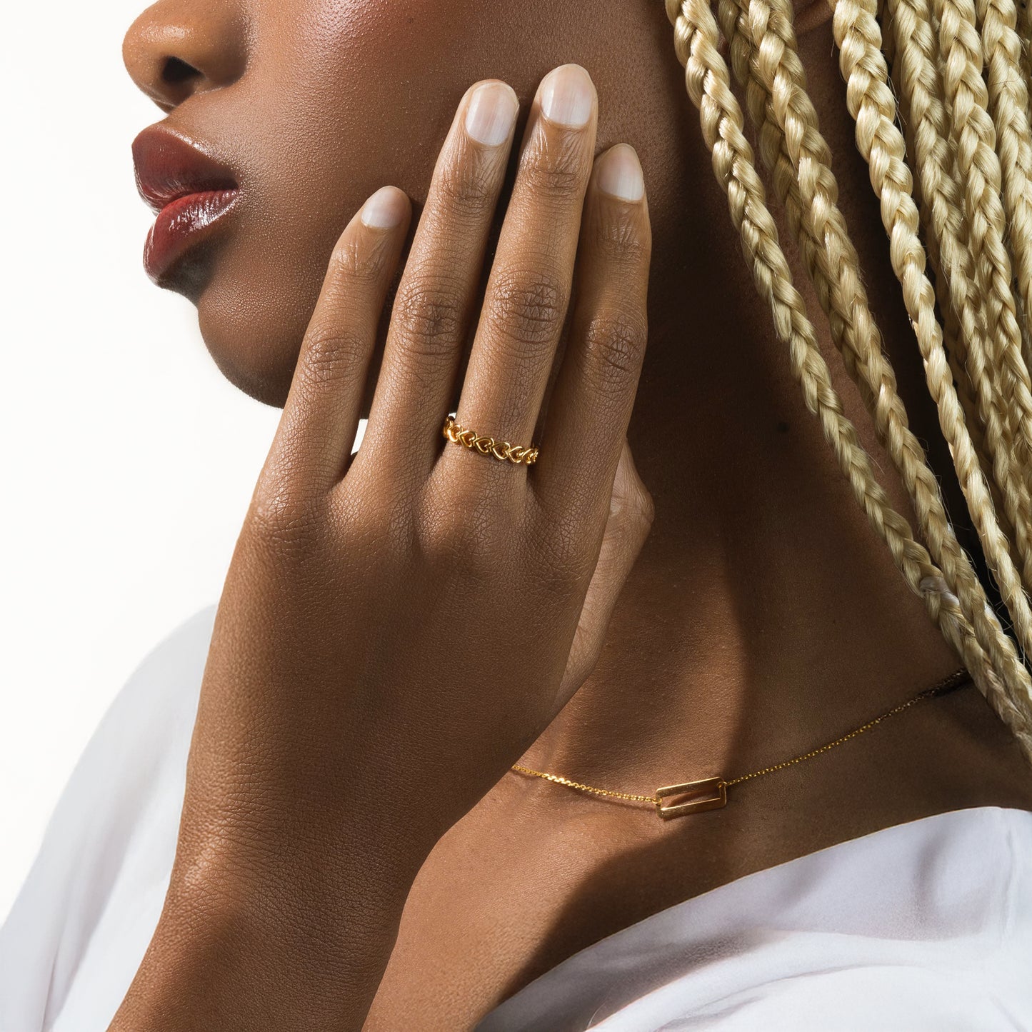 Close-up of a woman's hand with gold jewelry on a neutral background