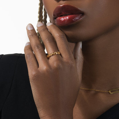 Close-up of a woman's hand with a gold ring and bracelet, wearing red lipstick.