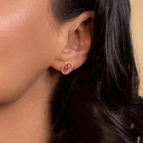 Close-up of an ear wearing a pink earring with a neutral background