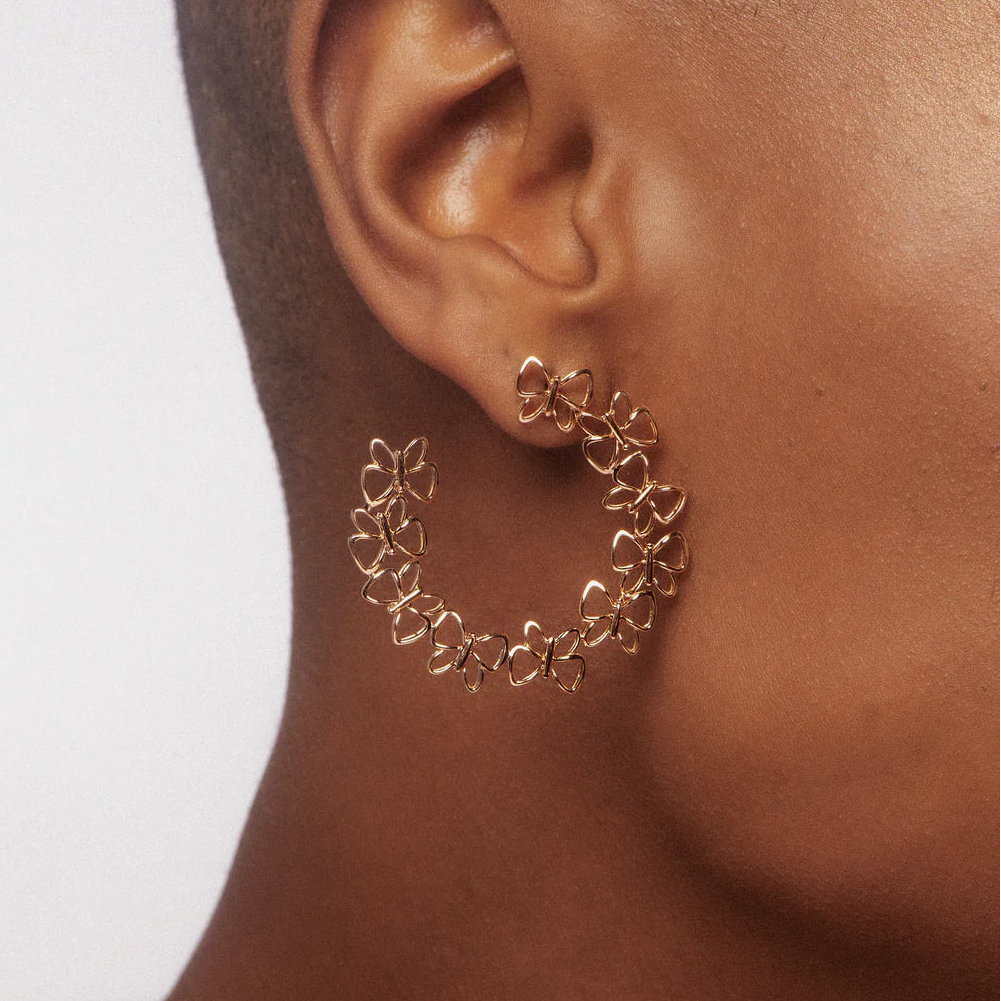 Gold hoop earrings worn by a person with a neutral background