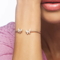 Close-up of a woman's arm wearing a butterfly bracelet with a blurred background