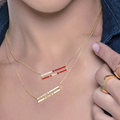 Woman wearing a gold necklace with red accents, close-up of neck and chest area.