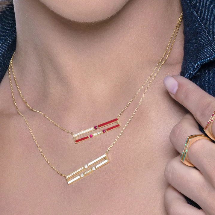 Woman wearing a gold necklace with red accents, close-up of neck and chest area.