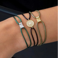Multiple bracelets with various designs on a wrist against a dark background
