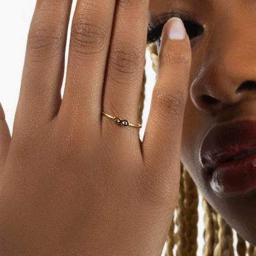Close-up of a hand wearing a gold ring with a blurred background