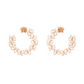 Rose gold floral hoop earrings on a white background