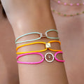 Close-up of a wrist wearing three colorful bracelets with decorative elements on a blurred background.