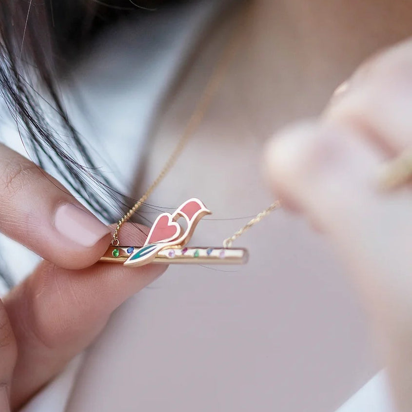 Close-up of a person wearing a necklace with a bird