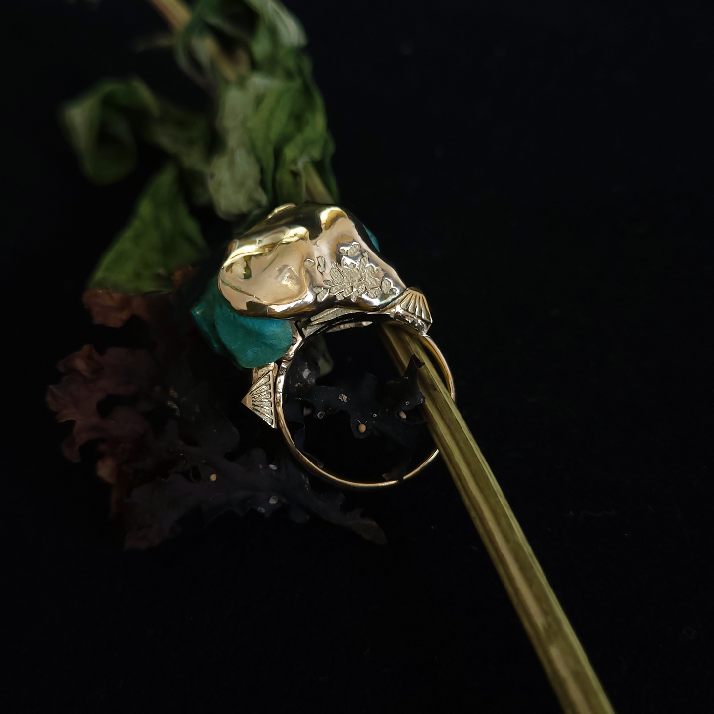 Gold ring with green gemstone on a black background
