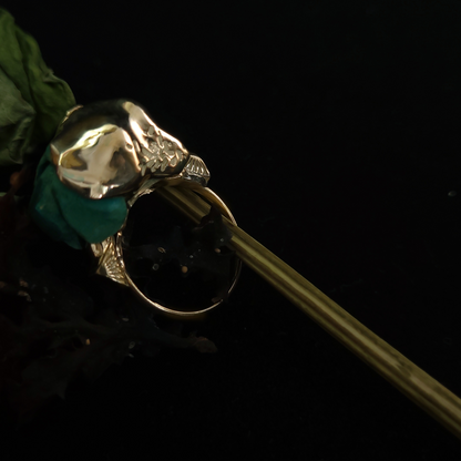 Gold ring with a green gemstone on a black background