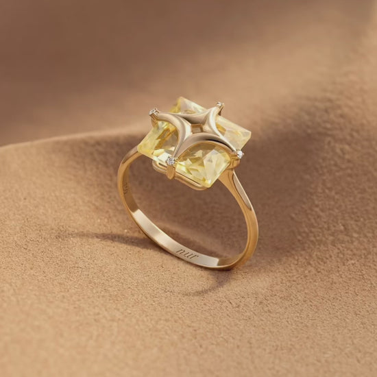 Gold ring with a yellow gemstone on a white background