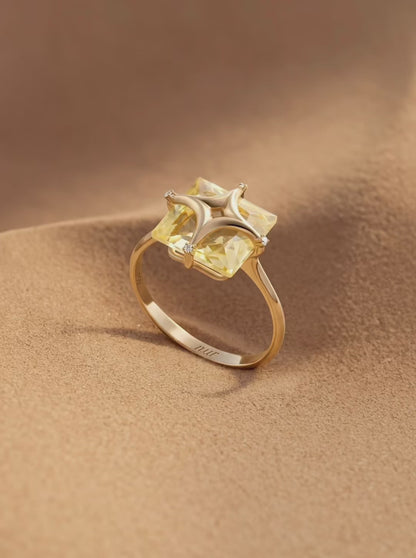 Gold ring with a yellow gemstone on a white background