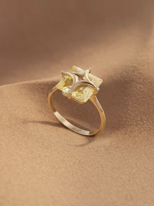 Gold ring with a yellow gemstone on a white background