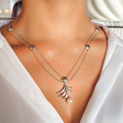 Necklace with a pendant featuring a pearl on a white blouse