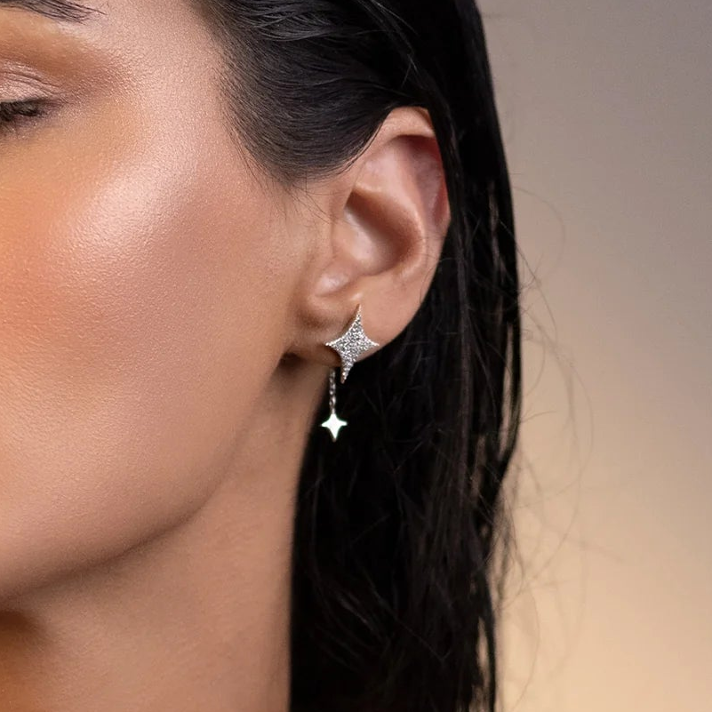 Close-up of a woman's ear wearing a star-shaped earring with a blurred background