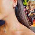 Close-up of a person wearing star-shaped earrings with a colorful background.