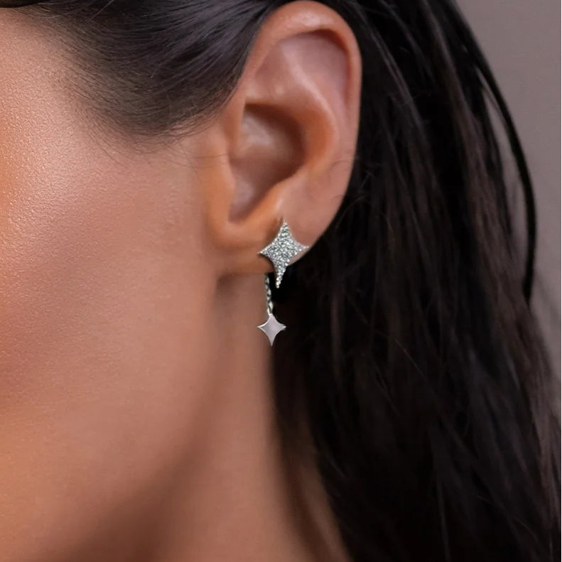 Close-up of an ear wearing a star-shaped earring with a blurred background