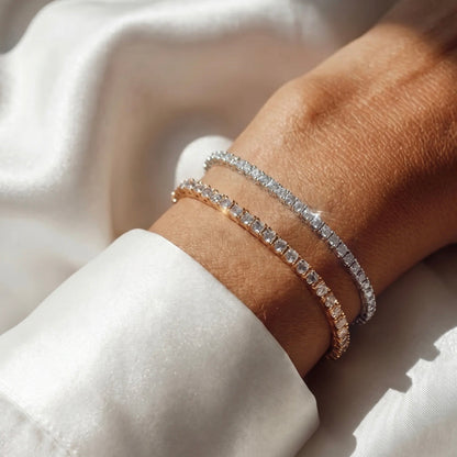 Close-up of a wrist wearing two diamond bracelets on a light background
