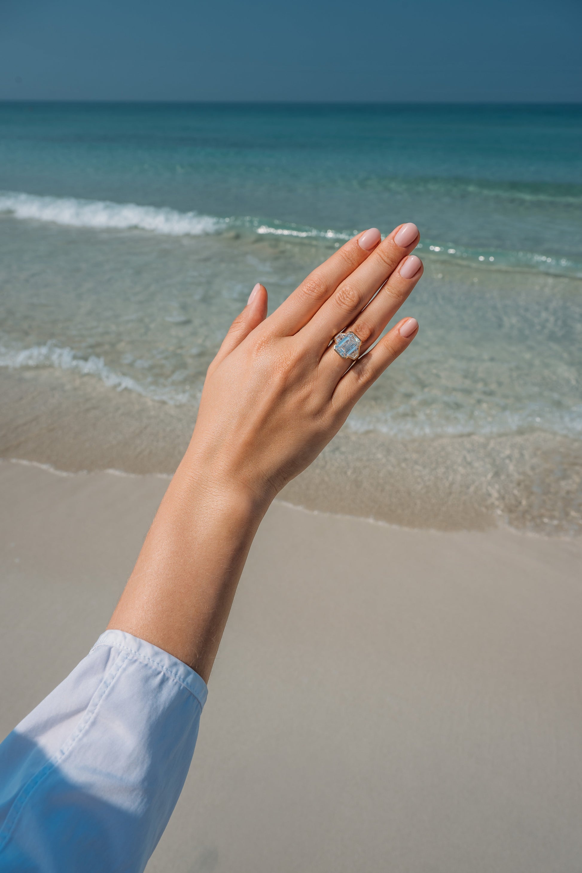 Verbesa Atelier emerald-cut lab-grown diamond three-stone engagement ring worn by the sea